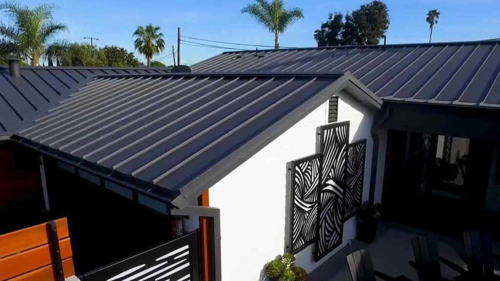 Modern house with a gray metal roof and white walls, featuring decorative black metal art panels. Palm trees are visible in the background. Modern house with a gray metal roof and white walls, featuring decorative black metal art panels. Palm trees are visible in the background.