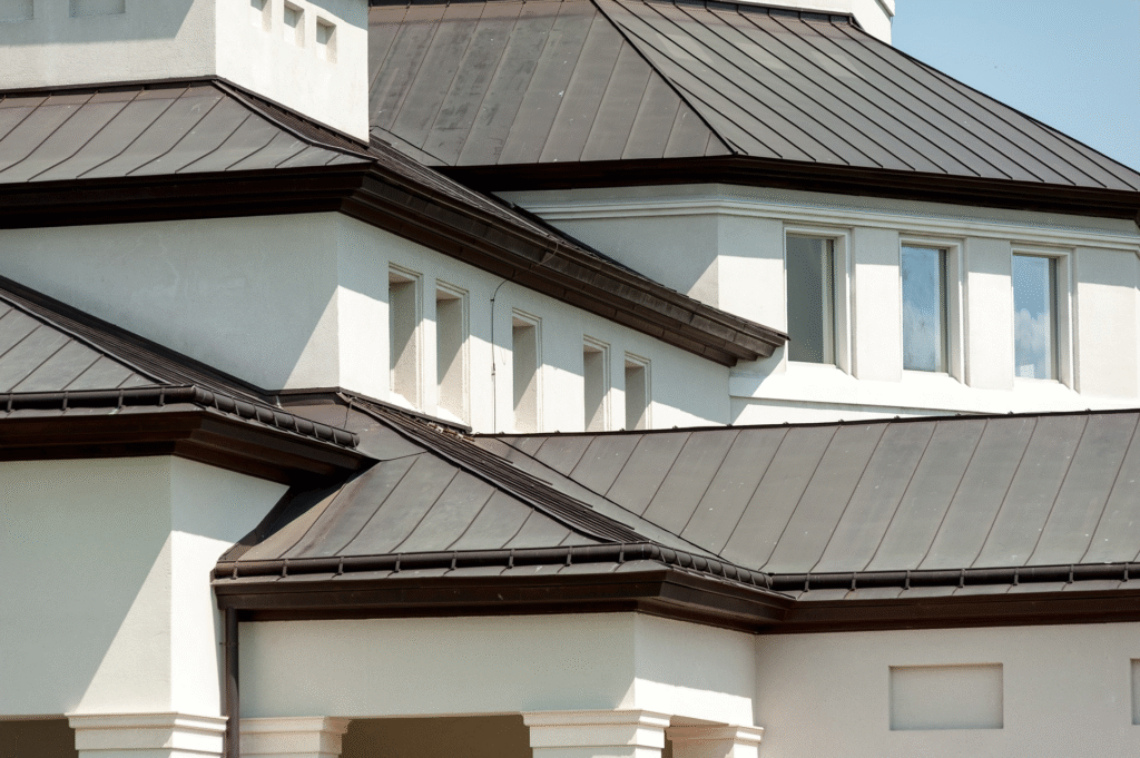 Modern building with white walls and multiple dark metal roofs, showcasing the appeal of metal roofing compared to traditional roofing, with several windows and striking architectural angles.