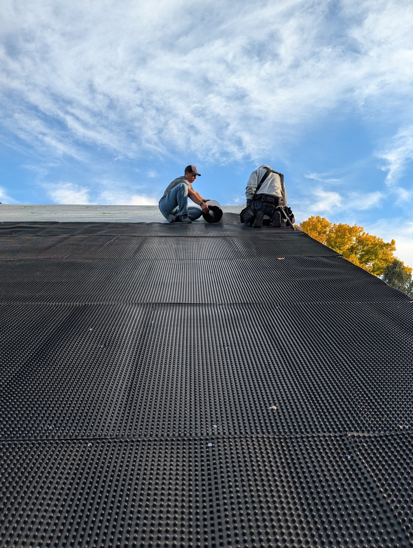WSM crew rolling out ventilated dimple mat on a roof deck, Grand Junction CO