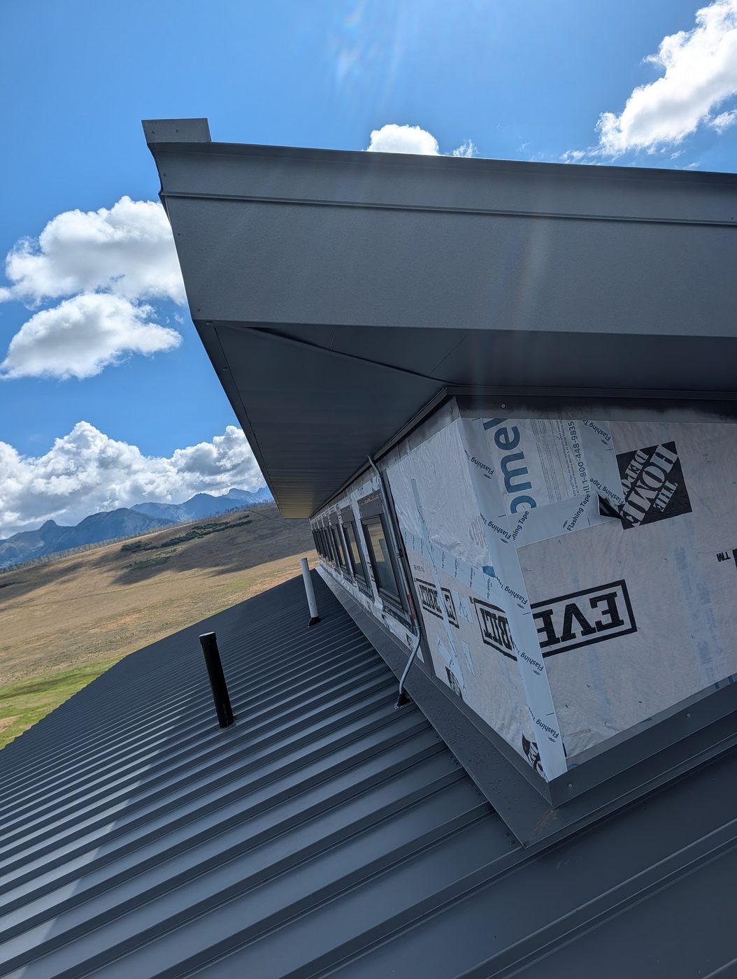 Deep metal fascia at the eave above a gray standing seam roof