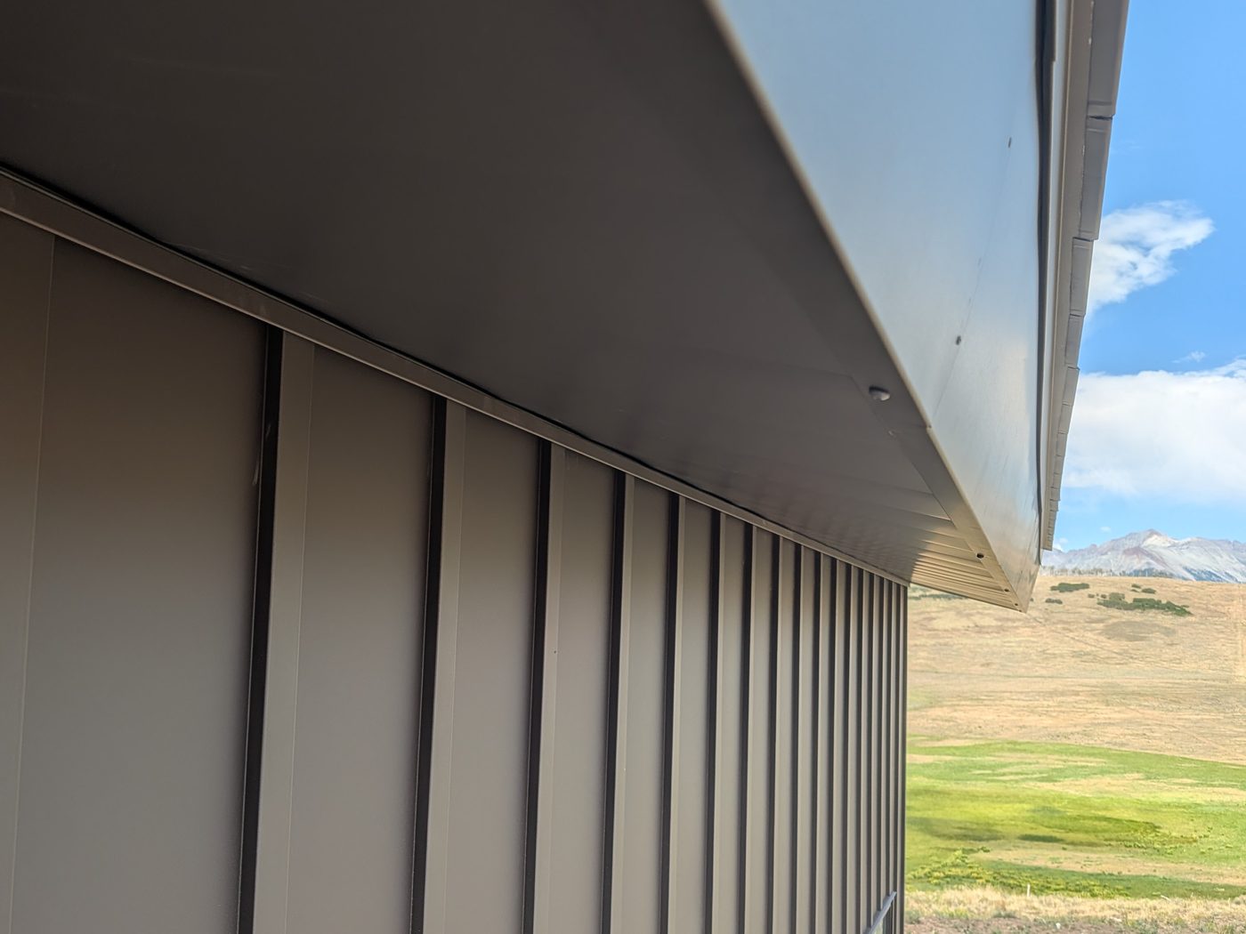 Matte Patina vertical metal siding under a deep metal eave with soffit, Wilson Mesa near Telluride