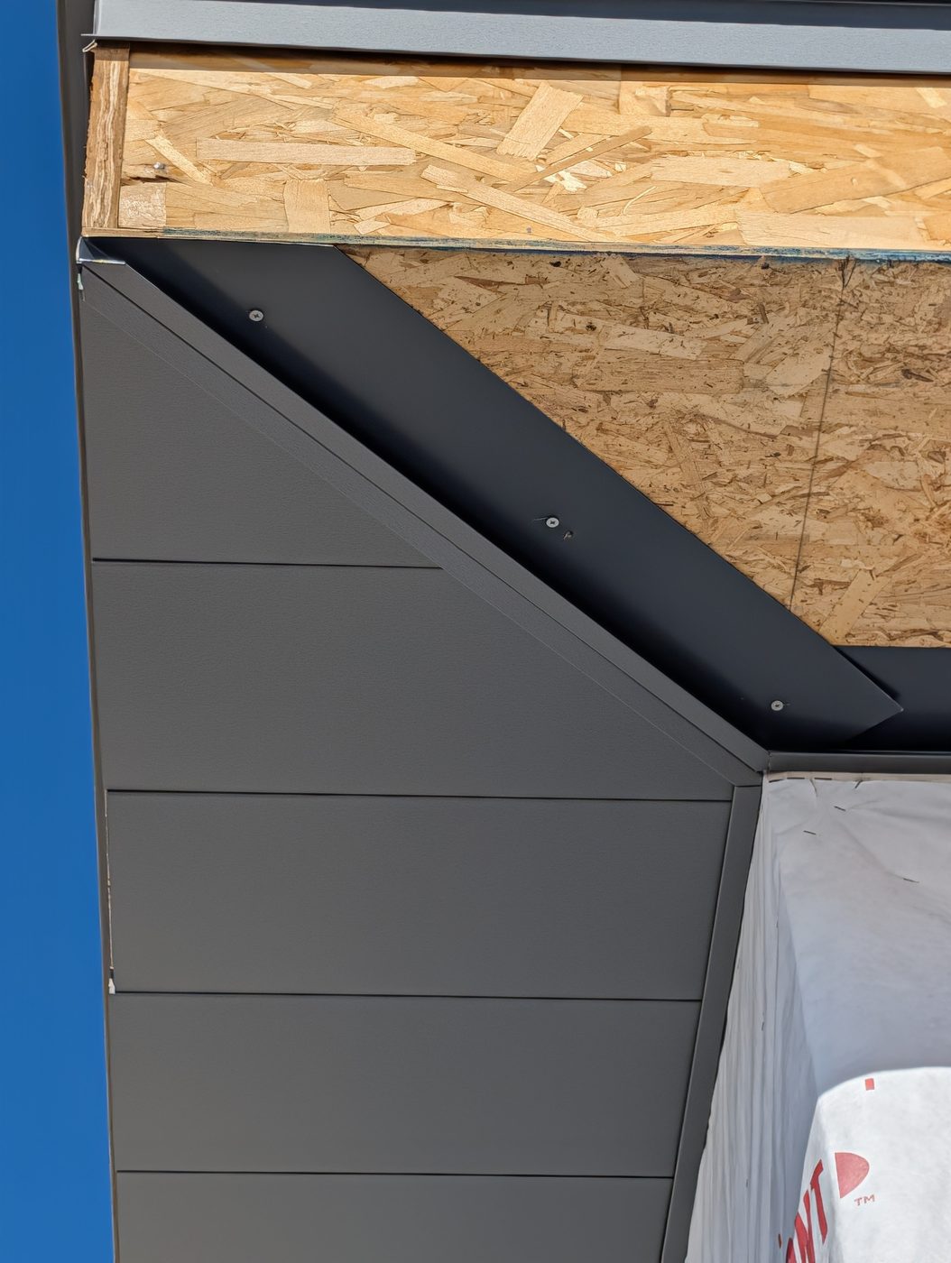 Metal soffit panels being installed under a deep eave